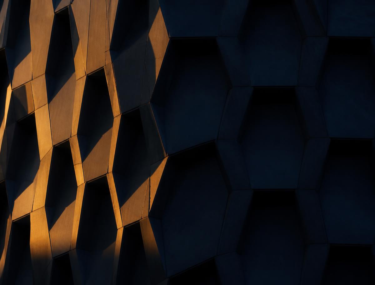 Amber light across a dark hexagonal architectural facade